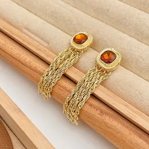 Detailed view of vintage court style long tassel earrings with amber zircon on wooden tray