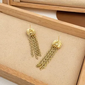 Macro detail view of elegant long gold-tone tassel earrings displayed in a wooden jewelry box