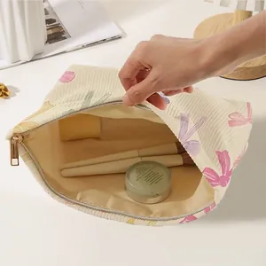 Large corduroy makeup bag with colorful bow print and gold zipper for cosmetic storage