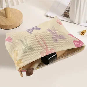 Large corduroy cosmetic bag featuring a colorful bow print and secure zipper closure
