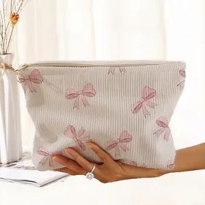 Detailed view of cream corduroy makeup bag with cute pink bow patterns and zipper