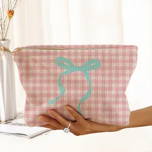 Detailed macro view of pink checkered corduroy makeup bag featuring a large teal bow print