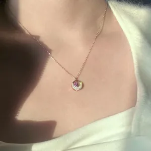 Detail of rose gold necklace featuring a crescent moon pendant with a purple stone.