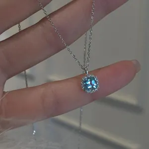 Detailed close-up of elegant silver necklace with square blue gemstone halo pendant