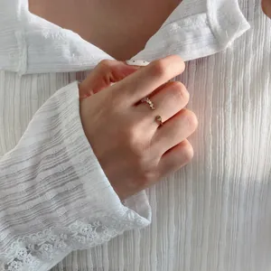 Vue détaillée d'une bague ouverte en cœur doré avec cristaux micro-pavés portée au doigt