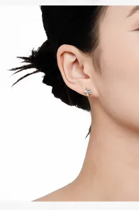 Close-up detail of a dainty S925 silver star stud earring with crystal on model's ear