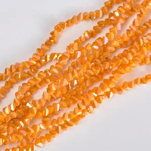 Macro detail of 4mm orange faceted triangular glass beads with electroplated finish