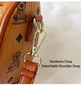 Close-up of golden hardware clasp and detachable strap on brown patterned handbag