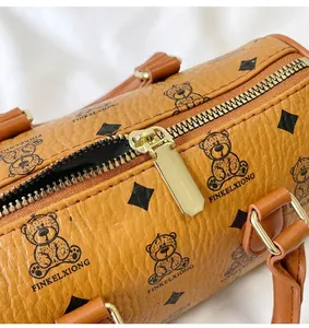 Close-up detail of smooth golden hardware zipper pull on bear-printed textured brown leather bag