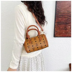 Detailed view of the cute bear pattern on a brown barrel-shaped crossbody handbag.