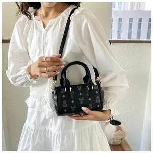Lifestyle shot of an Asian model carrying a black cylindrical handbag with bear pattern.