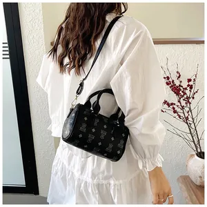 Detail view of a black crossbody handbag with bear print and diamond patterns on a model.