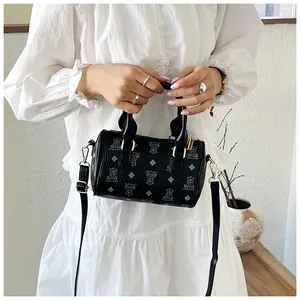 Detailed shot of a black teddy bear pattern handbag with top handles and shoulder strap.