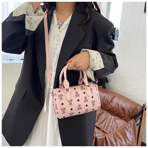 Detail view of a pink mini barrel handbag featuring a cute bear pattern and top handles