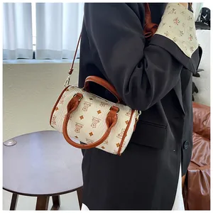 Detail view of a white barrel bag with bear pattern and brown handles