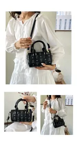 Detailed view of black barrel bag with cute bear patterns shown by model in white dress.