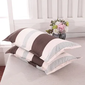 Detail of a pair of modern striped pillowcases in brown, white, and grey tones.