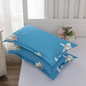 Pair of modern blue pillowcases with elegant white flower pattern on a white bed sheet