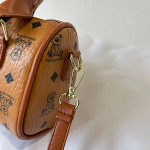 Close-up of stylish brown barrel bag featuring grain leather texture and golden metal clasp