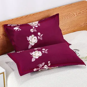 Pair of burgundy pillowcases with white floral print on a white textured bed sheet.