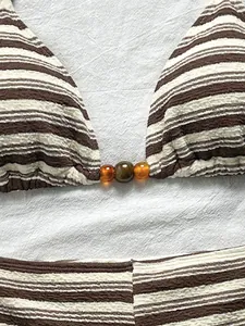 Primo piano di un bikini a righe marroni con tessuto strutturato e dettaglio di perline ambra