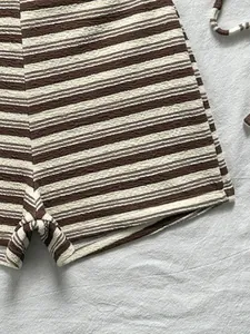Dettaglio dei pantaloncini bikini a righe marroni e bianche in tessuto testurizzato.