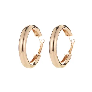 Close-up detail of polished gold large hoop earrings with a thick geometric design