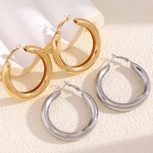 Detail of chunky gold and silver large hoop earrings with polished metallic finish