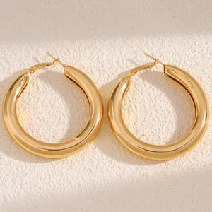 Close-up view of elegant chunky gold hoop earrings with a smooth polished metallic finish