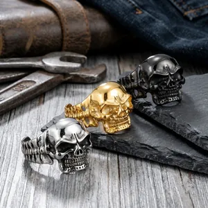 Detailed macro view of three punk style skull rings in silver, gold, and black finishes.