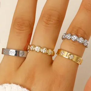 Close-up of stackable gold and silver stainless steel rings with zircon flower motifs.