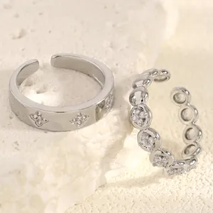 Close-up of silver stainless steel rings with zircon details on a stone background.