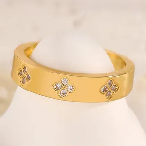 Detail macro view of a gold-colored stainless steel ring with inlaid zircon flower motifs