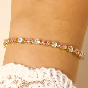 Dettaglio di un elegante bracciale dorato con cristalli rosa e trasparenti lucidi