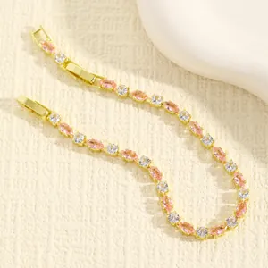 Elegante bracciale dorato con pietre marquise rosa e cristalli trasparenti su fondo testurizzato
