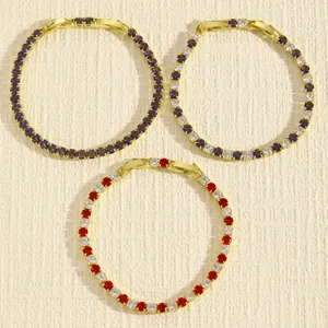 Dettaglio di bracciali tennis con pietre rosse, viola e bianche, placcati in oro.