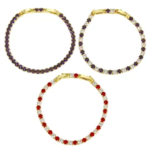 Dettaglio di tre braccialetti tennis dorati con pietre di zircone viola e rosse