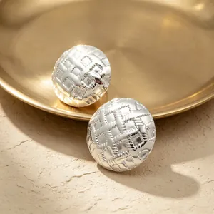 Macro view of silver-colored earrings with intricate woven grid pattern texture