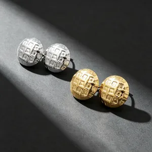 Detailed view of textured grid stud earrings in gold and silver stainless steel finish