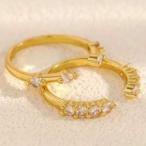 Close-up of gold-plated rings with shimmering zircon stones on textured surface.