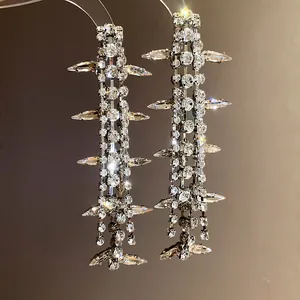 Macro view showing shimmering rhinestone tassel earrings with sharp geometric design elements.