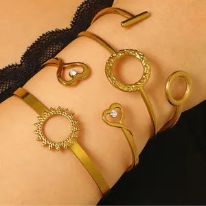 Detailed view of a stack of gold-plated open bangles with sun and heart-shaped charms