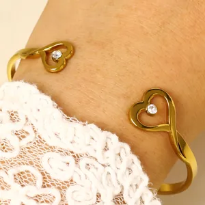 Detailed macro shot of a gold heart-shaped open bangle with sparkling crystals.