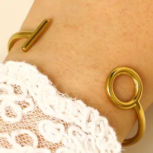 Close-up detail of a minimalist gold geometric cuff bracelet with bar and ring
