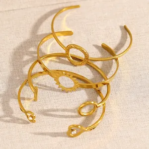 Detailed macro view of three gold-toned open cuff bracelets with sun and heart motifs