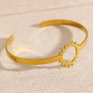 Detailed macro view of a gold-toned open bangle featuring a unique sunburst hollow design.