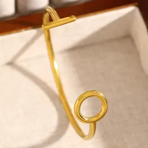 Close-up of gold geometric open bangle with minimalist T-bar and circle design