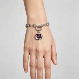 Gros plan d'un bracelet en acier titane vintage avec pendentif en cristal violet et fermoir OT