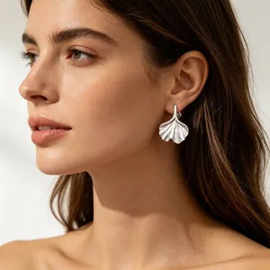 Elegant brushed silver ginkgo leaf earrings for women, minimalist fashion model shot.
