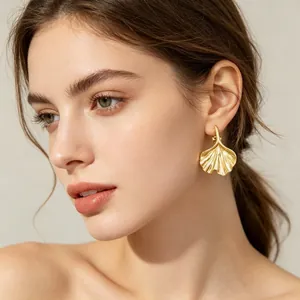 Detailed close-up view of elegant golden ginkgo leaf-shaped earrings on a female model